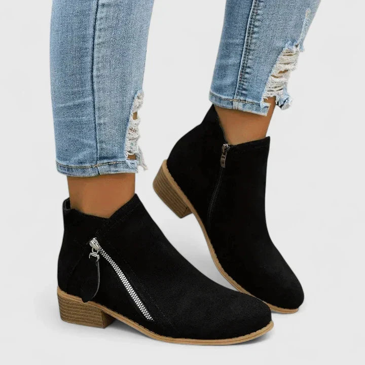 Woman wearing light blue vintage-style ankle boots, walking along a leafy street.