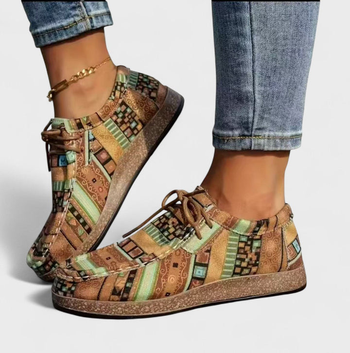 A woman wearing lace-up sneakers in a bold multicolour tribal print on a lightweight platform sole