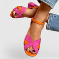 A woman wearing pink and orange open-toe block-heel sandals with an ankle strap, standing comfortably in a summer outfit.