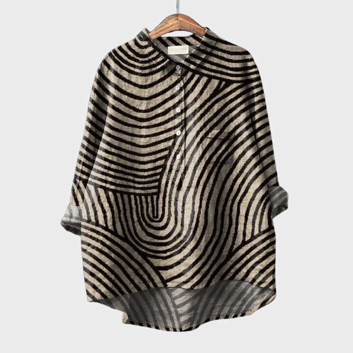 A woman wearing a beige summer blouse with a black wavy line print, looking polished and at ease on a warm day.