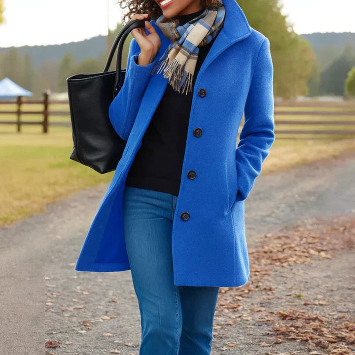 A woman wearing an elegant camel button-through coat over a sweater on a crisp fall day.