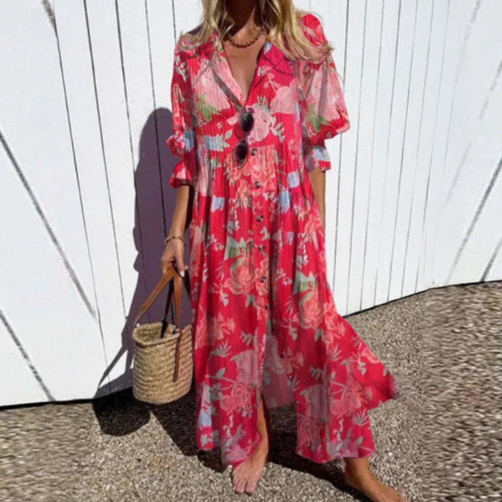 Woman wearing the Gail™ leaf print maxi dress with a button front, walking along the coast in a light breeze.