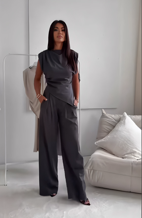 A woman wearing an asymmetric draped top with matching flowing wide pants.