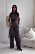 A woman wearing an asymmetric draped top with matching flowing wide pants.