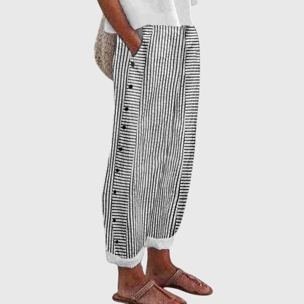 A woman wearing elegant everyday pants in a fine blue stripe with a wide cut and side buttons.