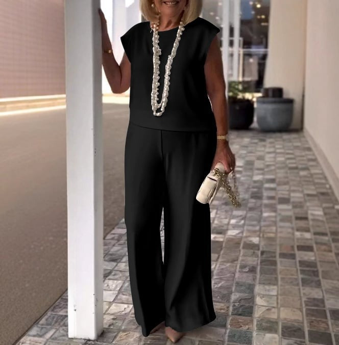A woman wearing a flowing short-sleeve top with graceful wide-leg pants.