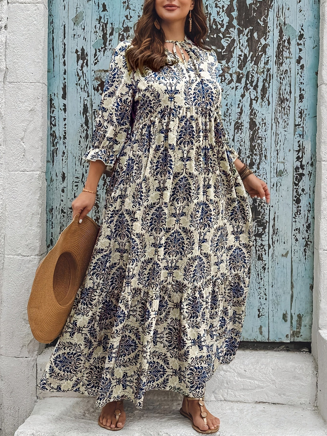 Woman strolling by the sea in the Melanie mosaic print maxi dress with a keyhole neckline and bow detail.