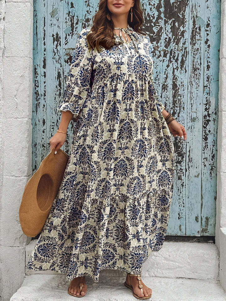 Woman strolling by the sea in the Melanie mosaic print maxi dress with a keyhole neckline and bow detail.