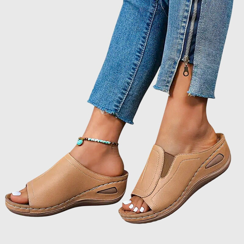 Tan open-toe wedge slides with a smooth one-piece upper and a cushioned wedge sole.