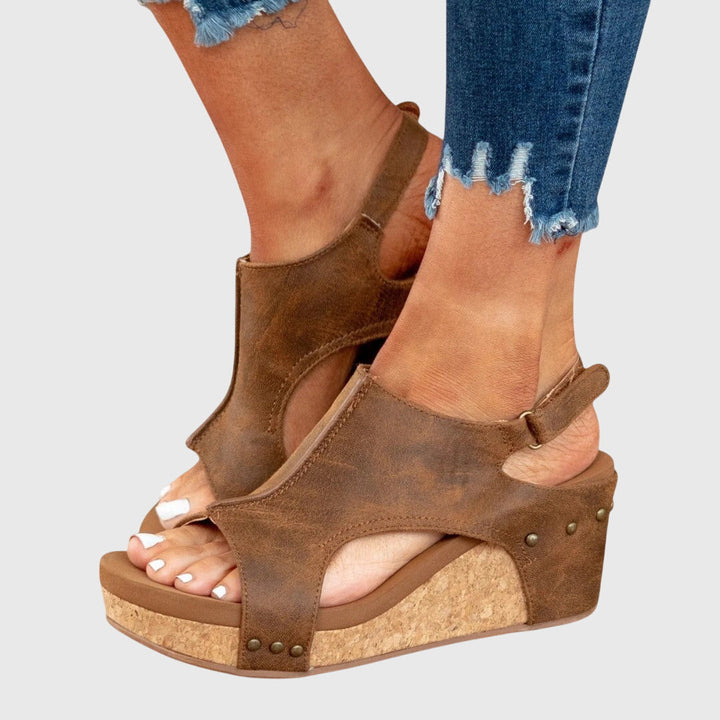 A woman in taupe wedge sandals with an open front, out shopping on a warm day.