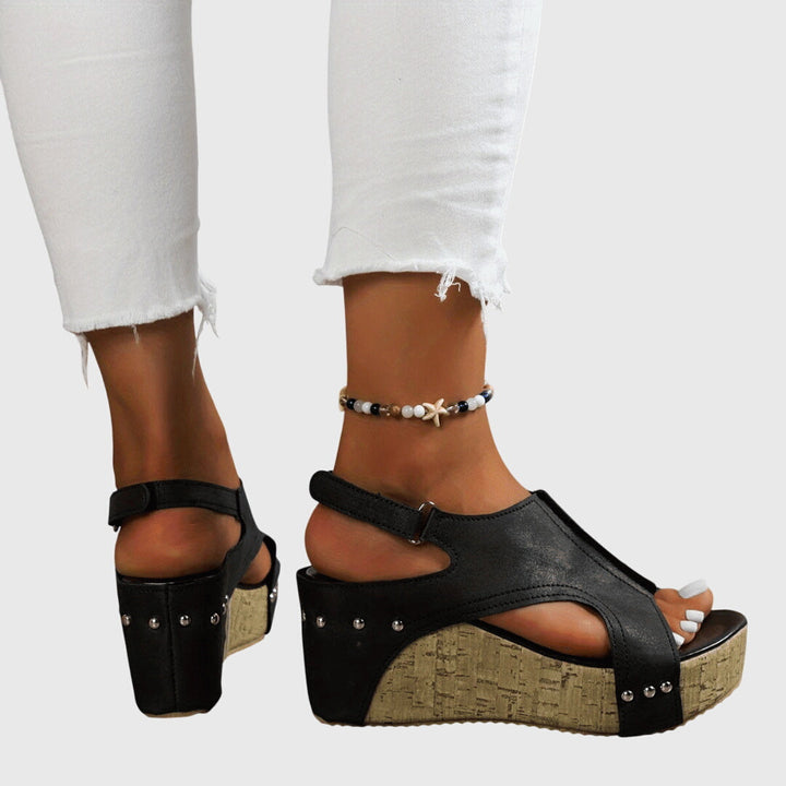 A woman in studded wedge sandals with an open front at a summer event.