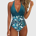 A woman by the sea in an elegant V-neck printed swimsuit, confident and relaxed in the sun.