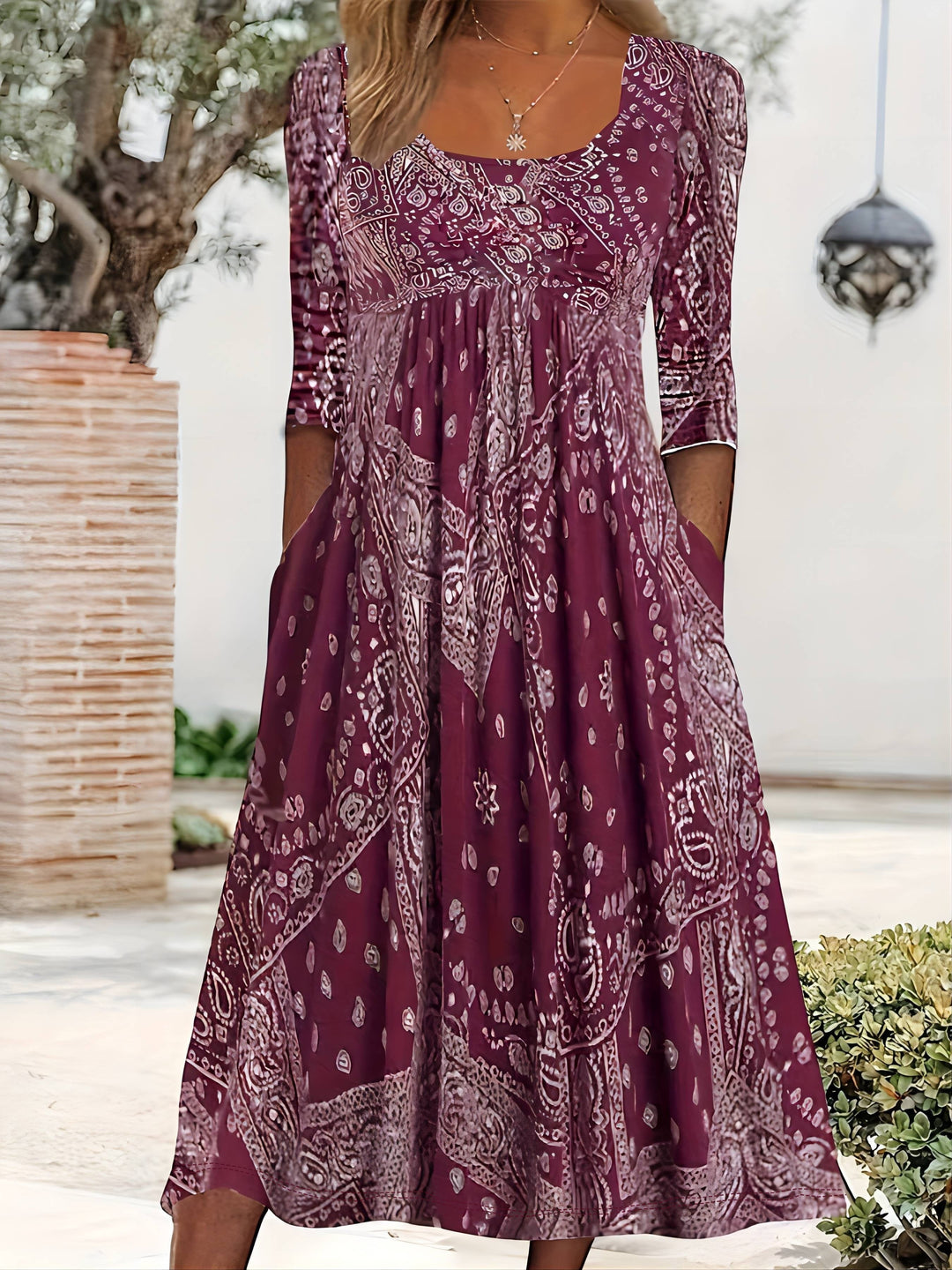 A woman wearing the Maria long sleeve grey paisley midi dress with a square neckline and flowing skirt, styled for a relaxed day out.