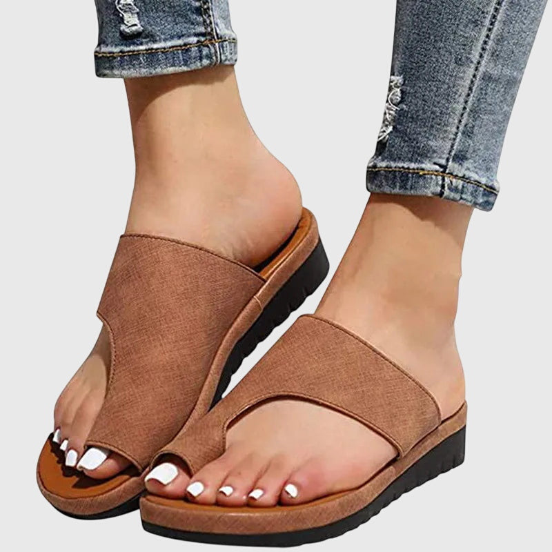 A woman in taupe toe-loop supportive sandals standing gracefully, feet cushioned and at ease.