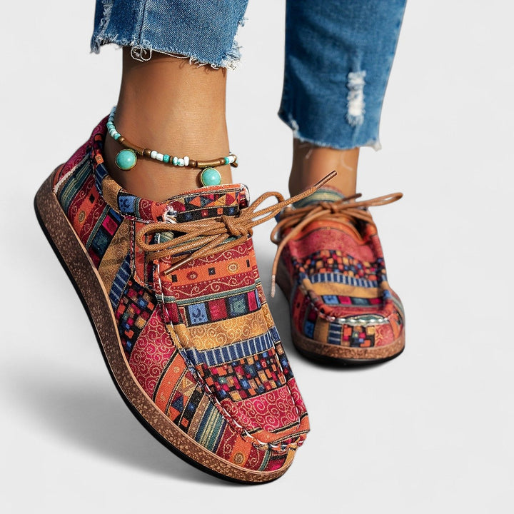 A woman wearing lace-up sneakers in a bold multicolour tribal print on a lightweight platform sole