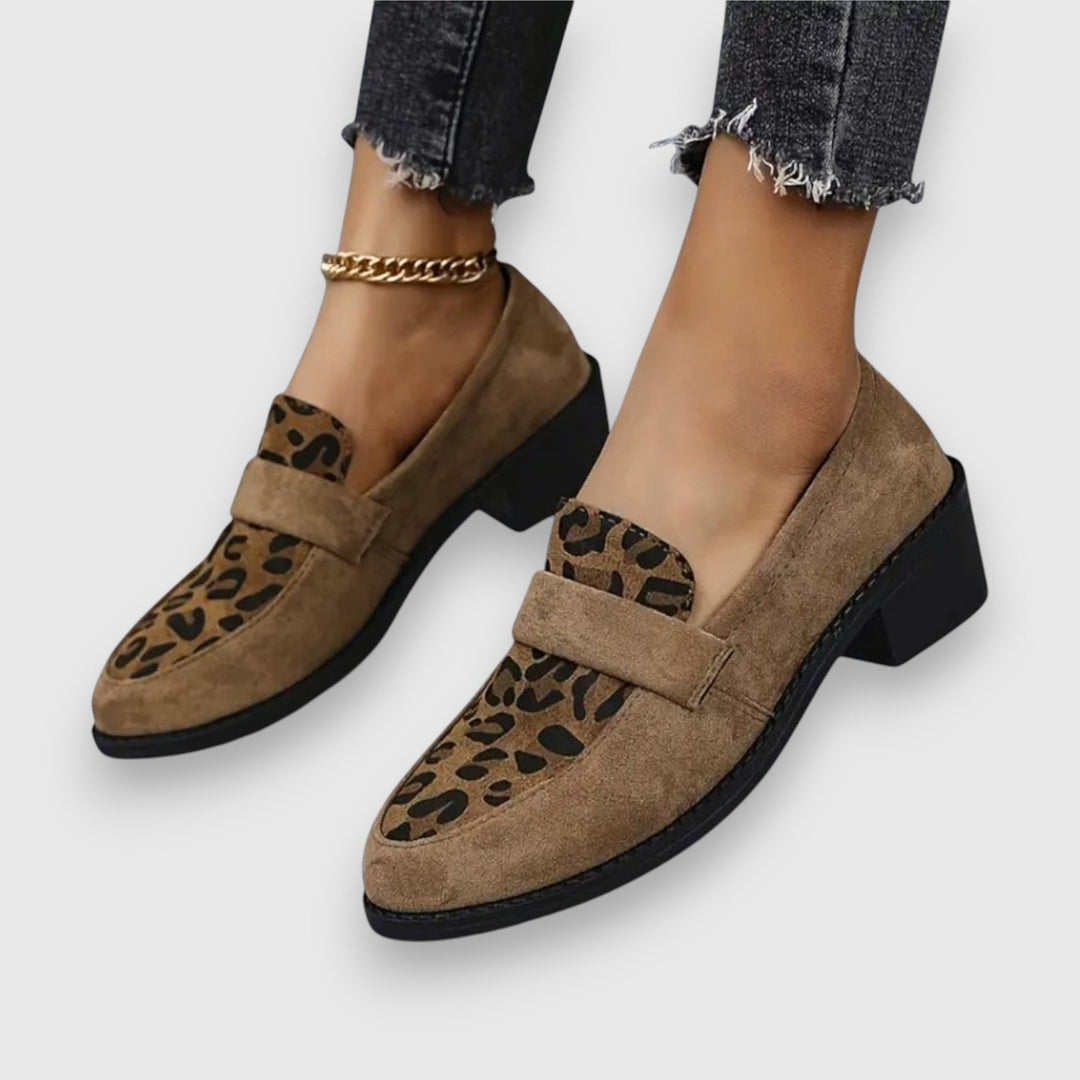 A woman wearing tan leopard print loafers with a low block heel, styled with jeans.