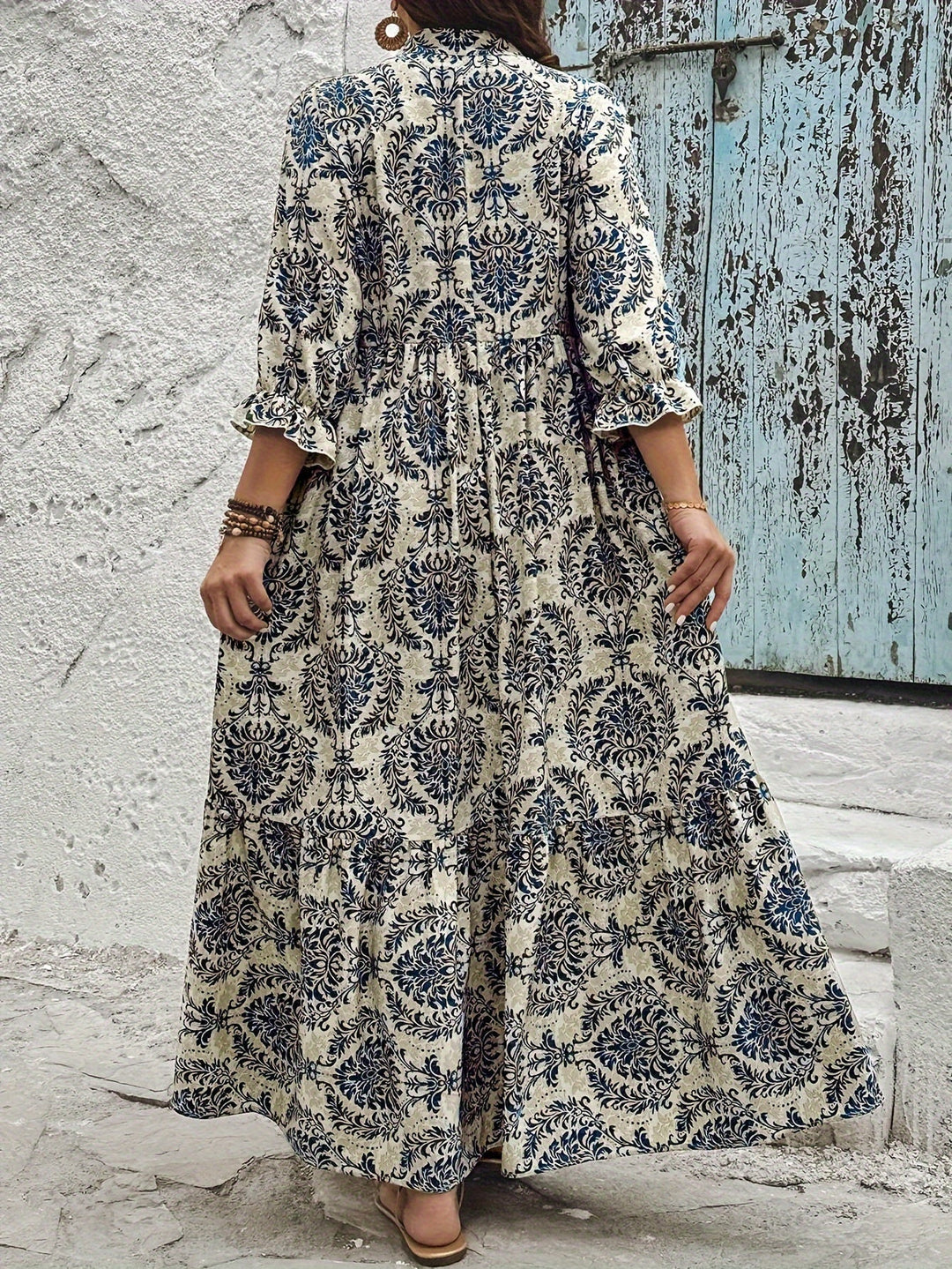 Woman strolling by the sea in the Melanie mosaic print maxi dress with a keyhole neckline and bow detail.