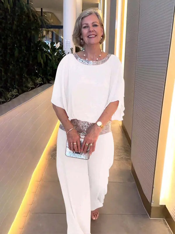A woman wearing an embellished blouse-style top with softly flowing wide evening pants.
