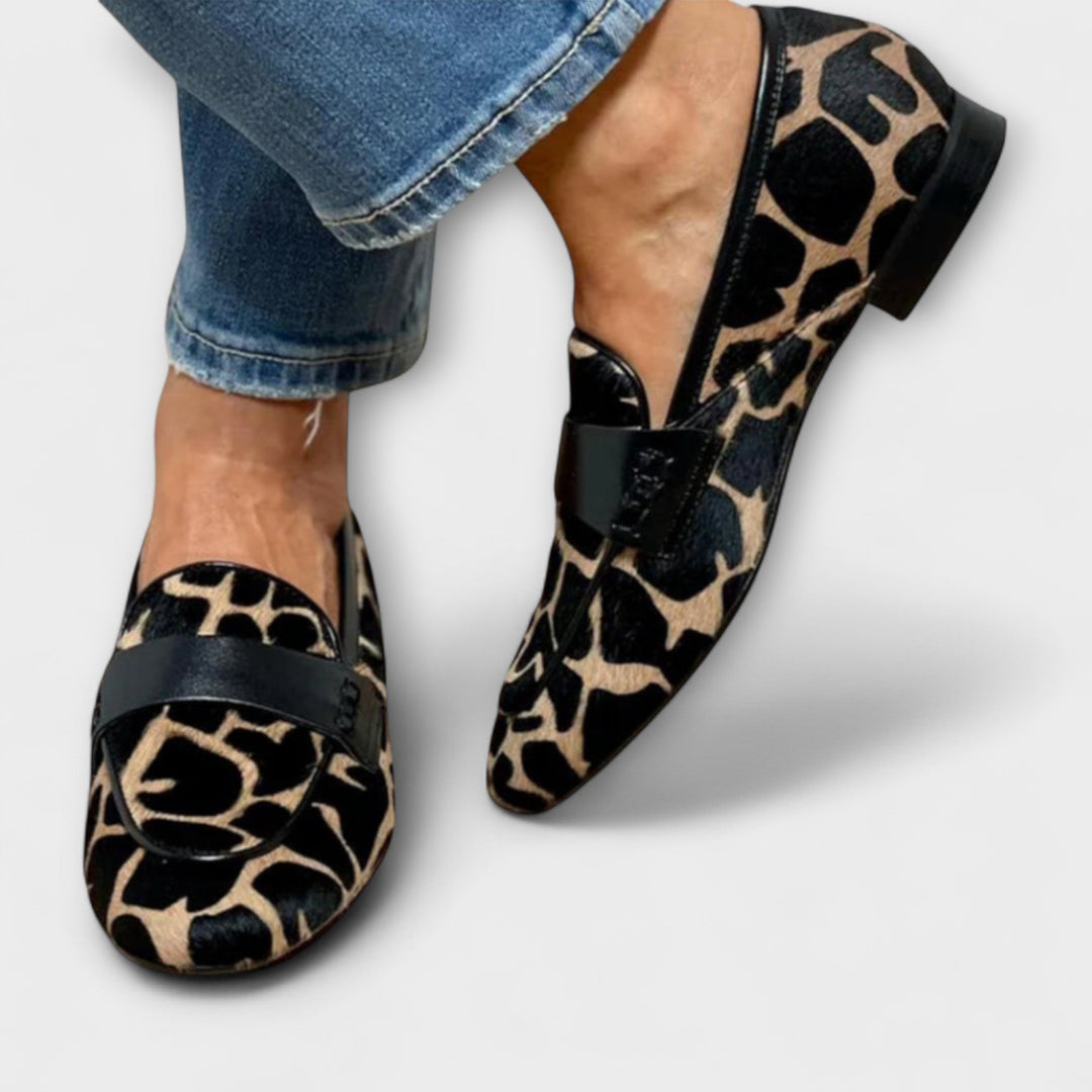 A woman in leopard-print loafers stepping out on a city pavement.