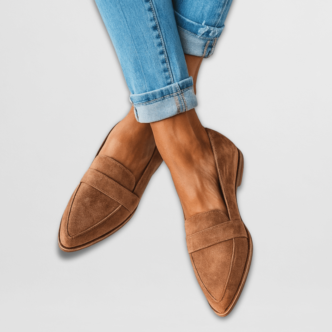 A woman wearing warm tan pointed-toe loafers with cuffed cropped jeans.
