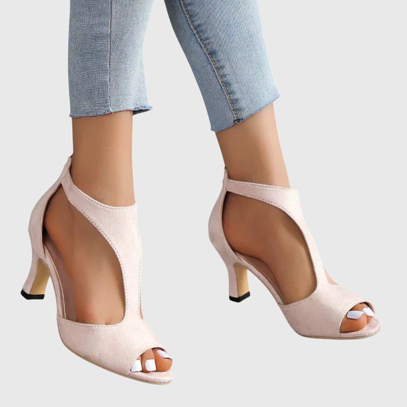 A woman wearing flexible orthopaedic heels, standing comfortably in a polished everyday outfit.