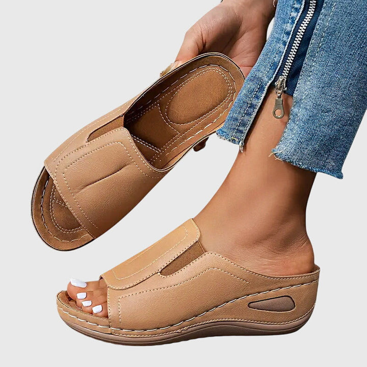 Tan open-toe wedge slides with a smooth one-piece upper and a cushioned wedge sole.