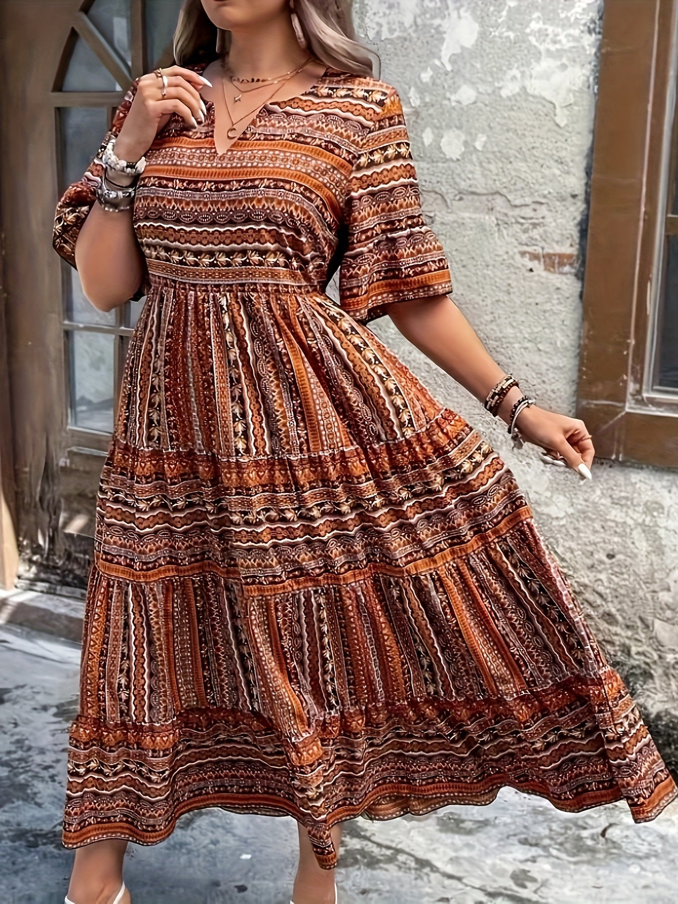 Woman wearing a flowing bohemian maxi dress with intricate pattern and ruffled details.