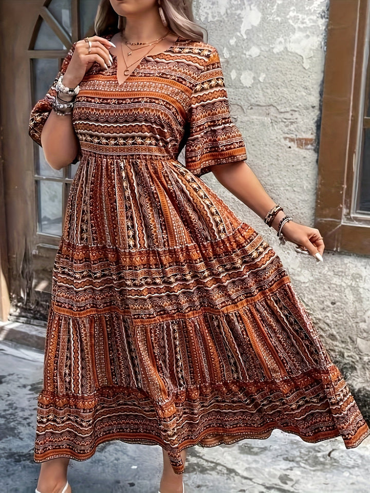 Woman wearing a flowing bohemian maxi dress with intricate pattern and ruffled details.