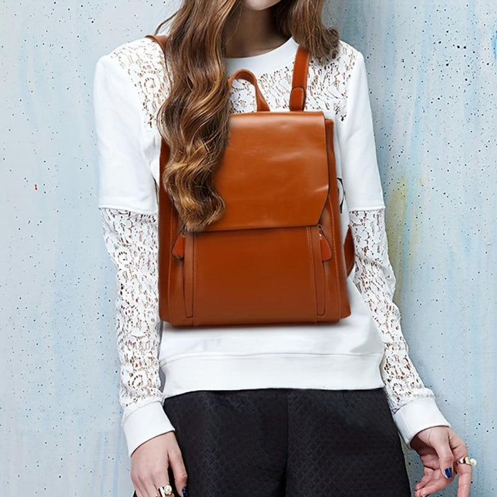A woman wearing a padded vintage-style backpack over both shoulders while walking through the city.