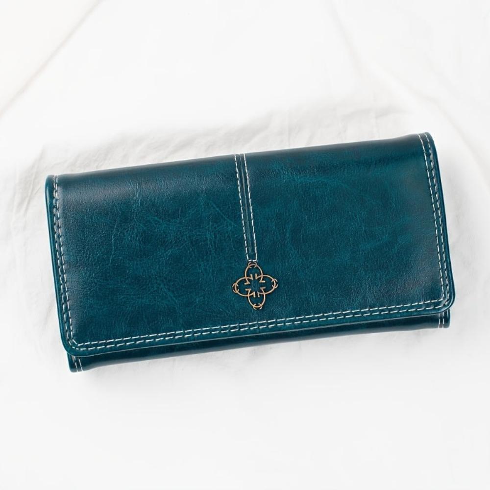 A woman holding a long flap-over wallet, tucking a card into its slot.