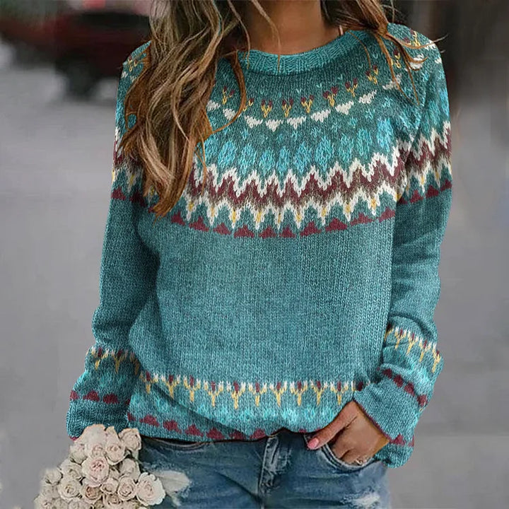 A woman wearing a teal sweater with a colourful retro zigzag pattern and a round neck, relaxed and cosy for fall.