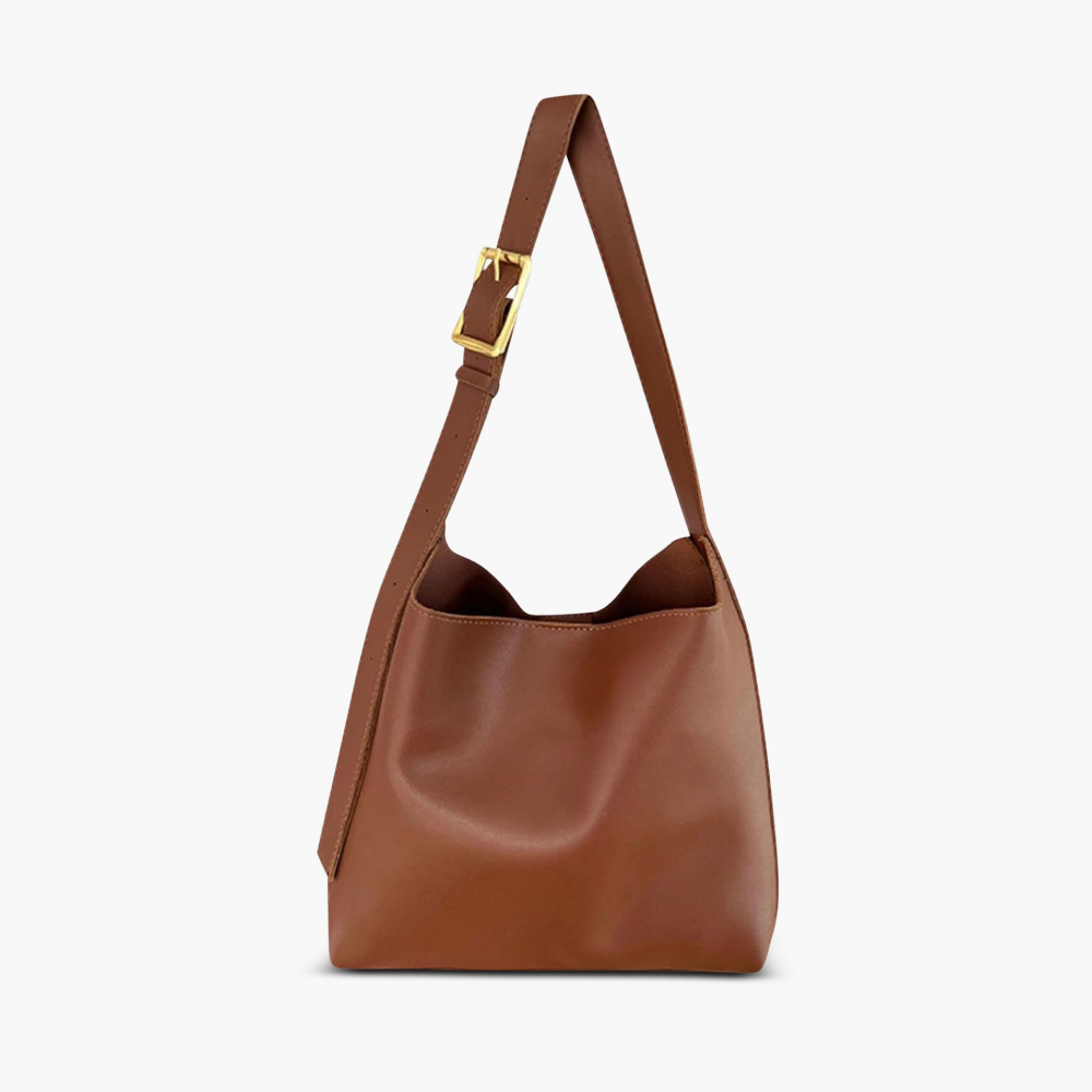 A tan bucket-style shoulder bag with an adjustable buckled strap