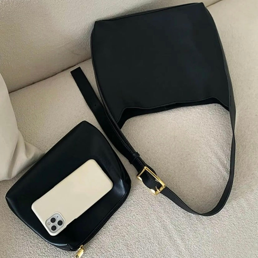 A tan bucket-style shoulder bag with an adjustable buckled strap