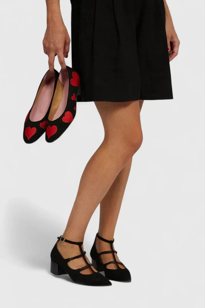 A woman standing gracefully in low wide-fit comfort heels with a cushioned footbed.