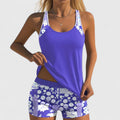 A woman wearing a blue tankini set with a loose tank top and matching floral-print shorts.