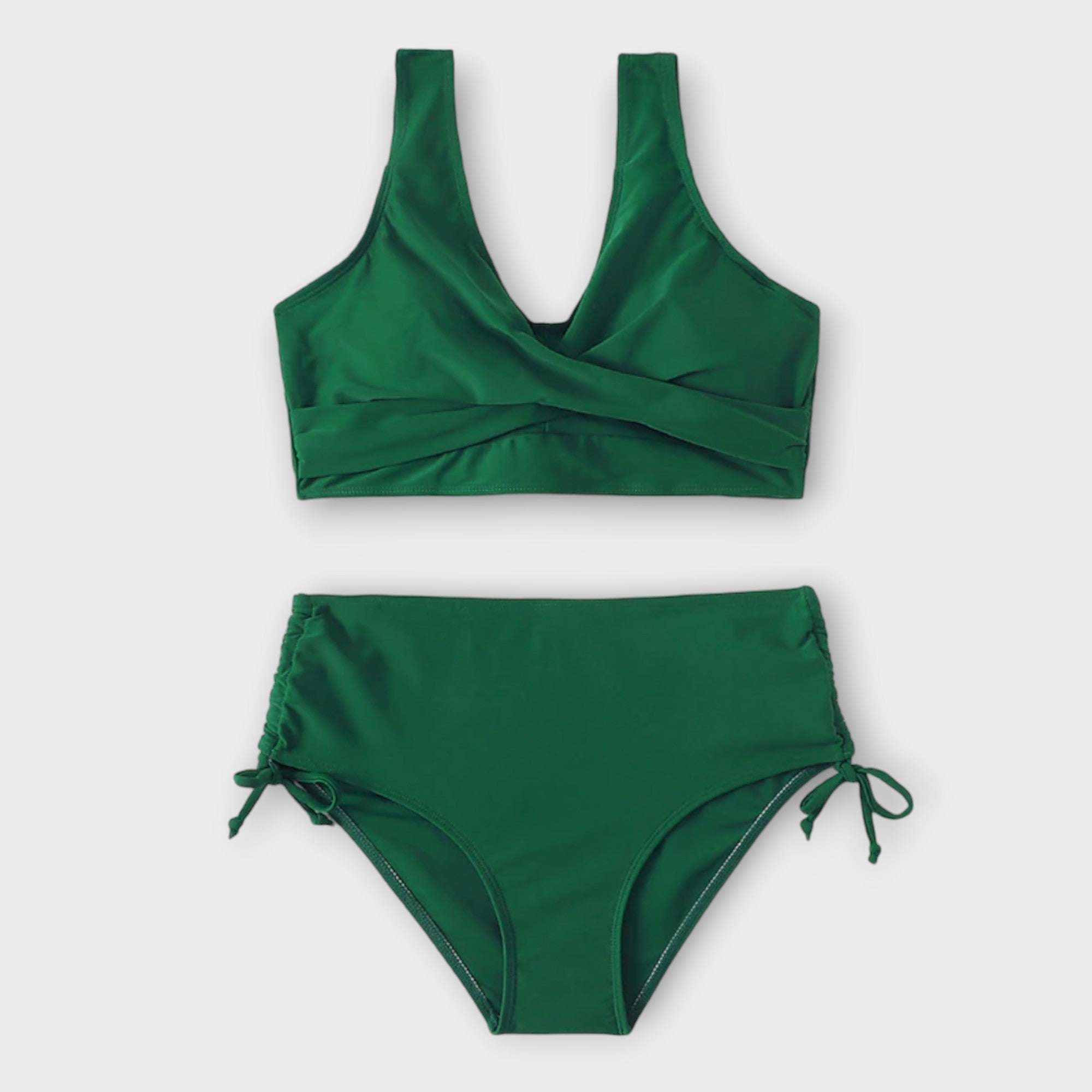 A woman in a plain green two-piece bikini set with a wrap front, relaxed and smiling in the sun.