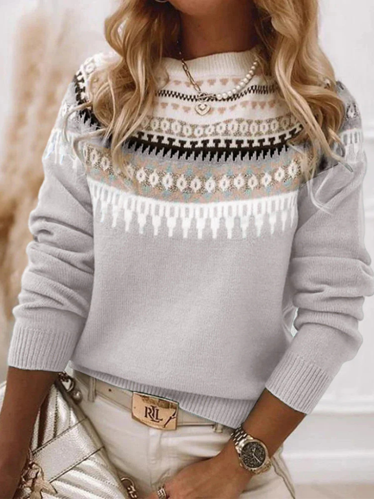 A woman wearing a soft powder-blue sweater with a cream, tan and black Nordic yoke pattern
