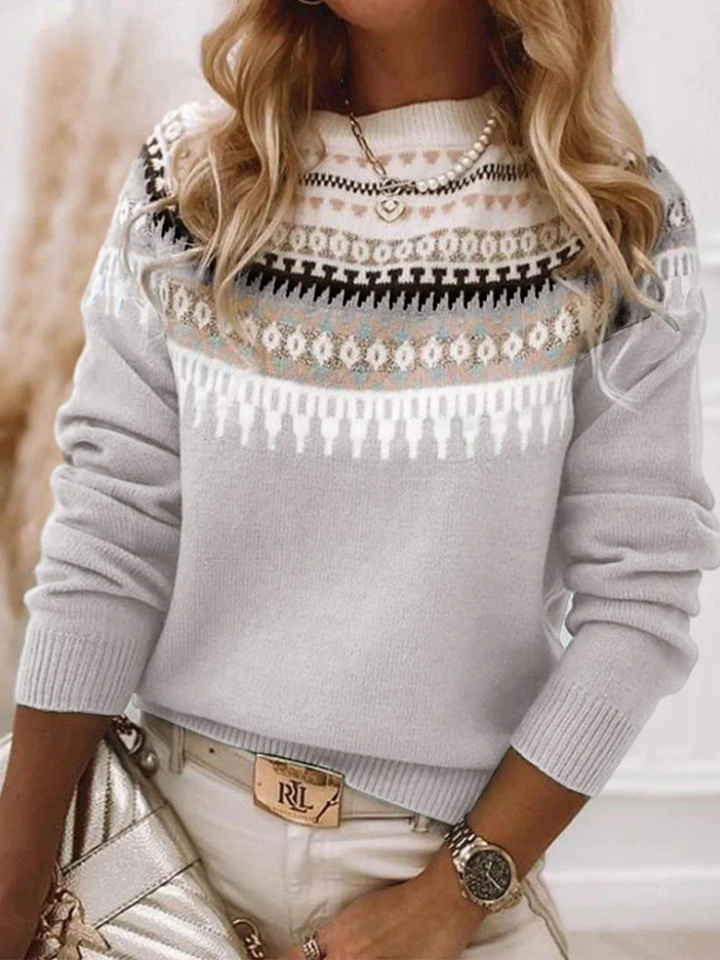 A woman wearing a soft powder-blue sweater with a cream, tan and black Nordic yoke pattern