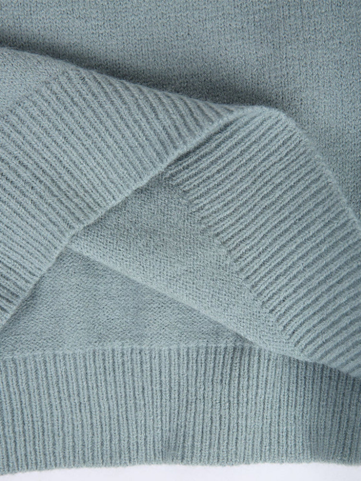 A woman wearing a soft powder-blue sweater with a cream, tan and black Nordic yoke pattern