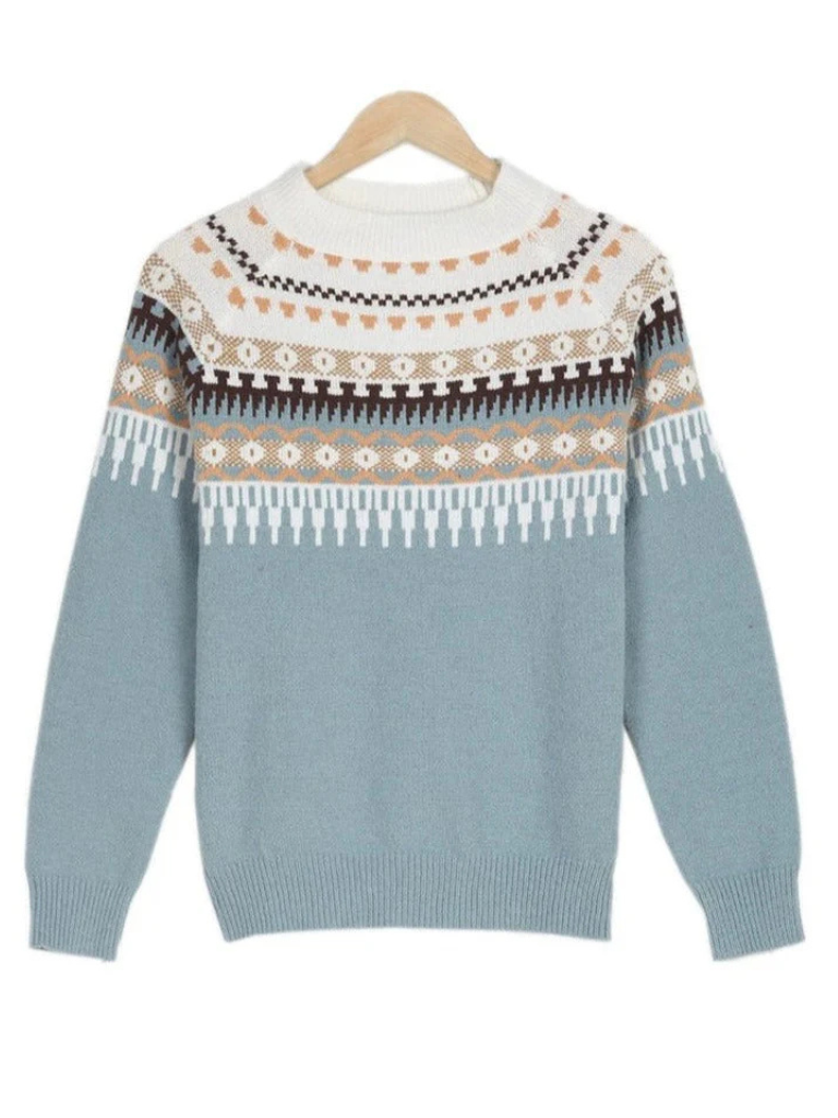 A woman wearing a soft powder-blue sweater with a cream, tan and black Nordic yoke pattern