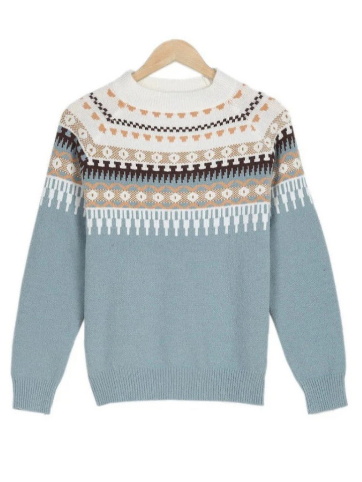 A woman wearing a soft powder-blue sweater with a cream, tan and black Nordic yoke pattern