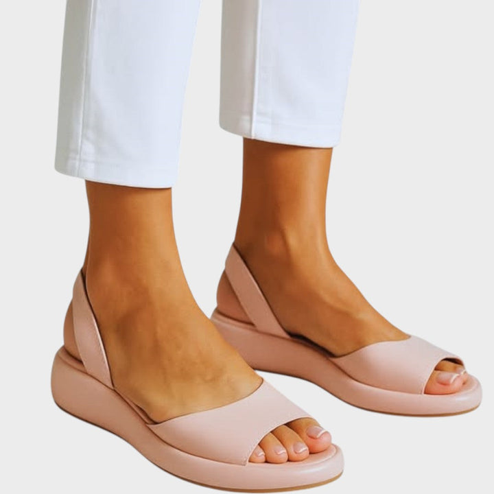 A woman walking gracefully in lightweight orthopaedic sandals with an adjustable strap on a sunny day.