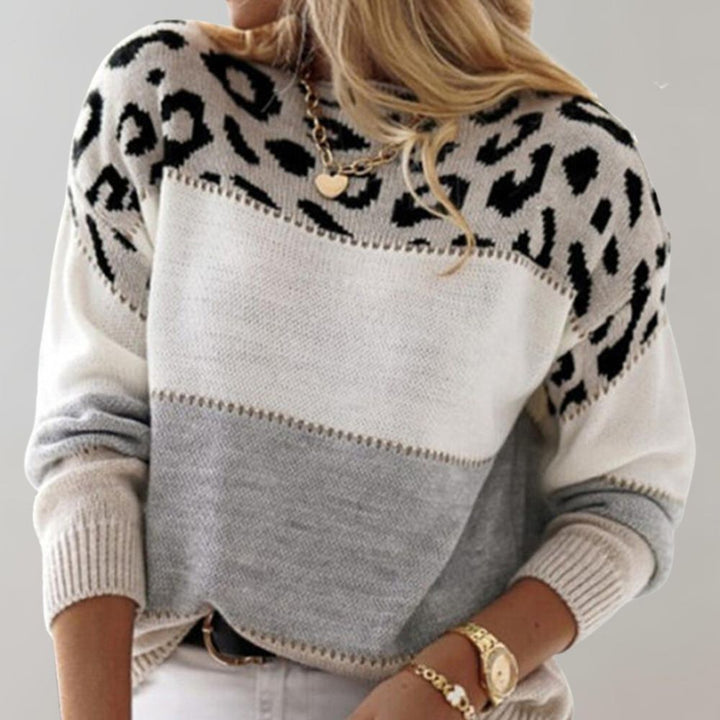 A woman wearing a grey leopard-print sweater, cosy and stylish, paired with jeans.