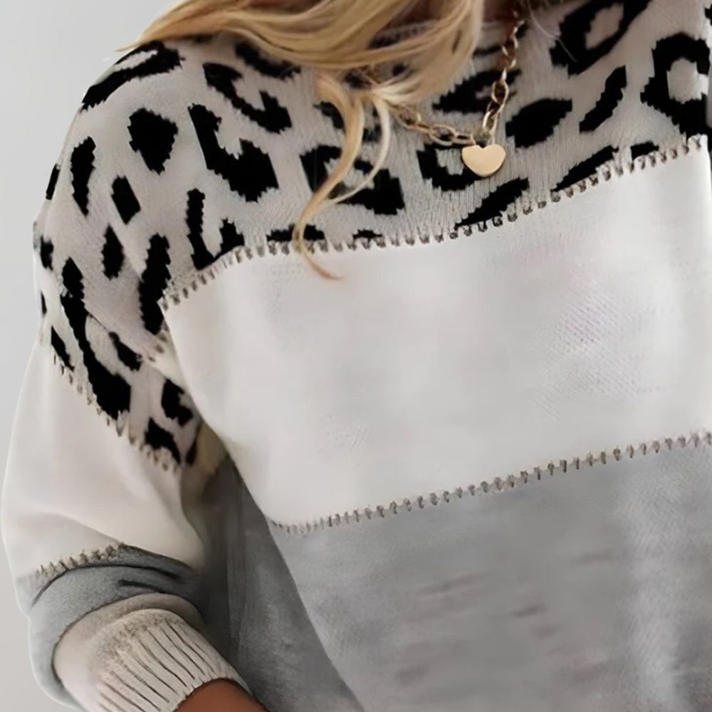 A woman wearing a grey leopard-print sweater, cosy and stylish, paired with jeans.