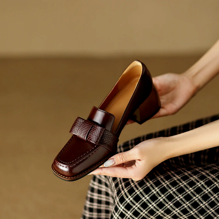 A woman wearing classic loafers with a subtle knot detail and tailored pants