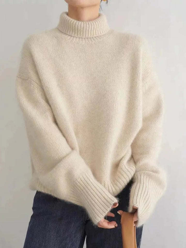 A woman wearing a beige roll-neck sweater, relaxed and warm, paired with pants.