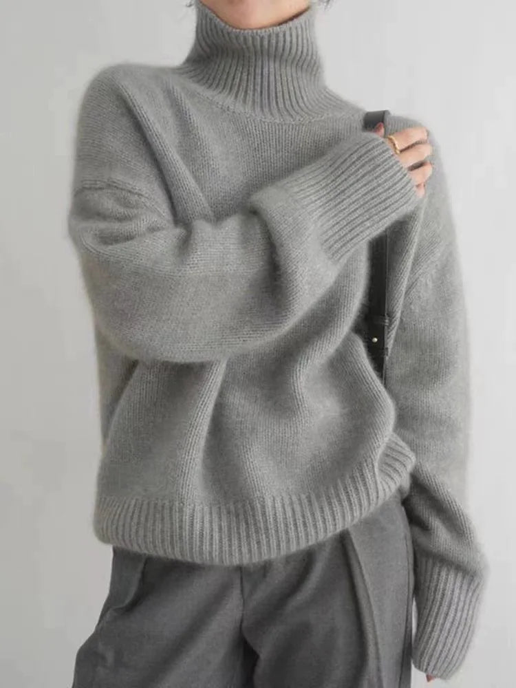 A woman wearing a beige roll-neck sweater, relaxed and warm, paired with pants.