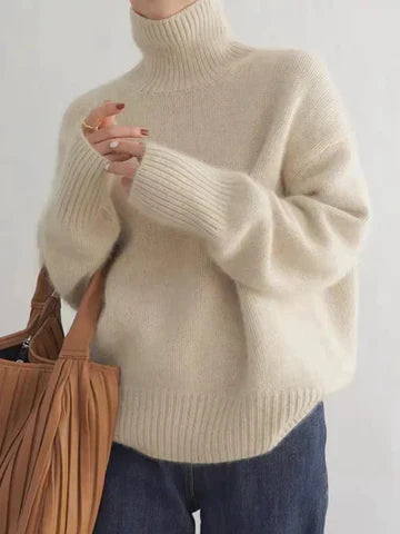 A woman wearing a beige roll-neck sweater, relaxed and warm, paired with pants.