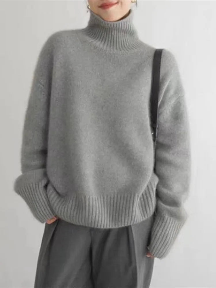 A woman wearing a beige roll-neck sweater, relaxed and warm, paired with pants.