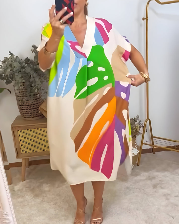 A woman wearing a colourful abstract print dress with a V-neckline and short sleeves.